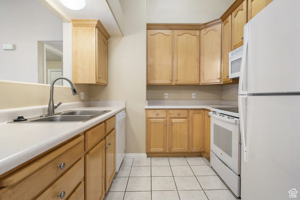 Kitchen with white appliances, light countertops, light tile patterned flooring, and light brown cabinetry
