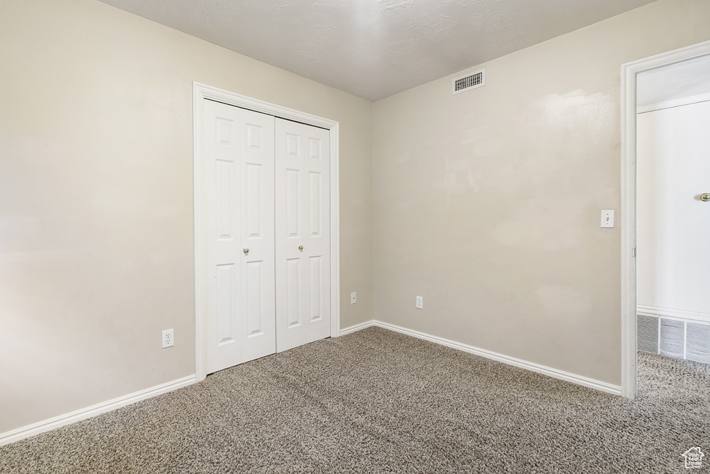 Unfurnished bedroom featuring carpet flooring and a closet