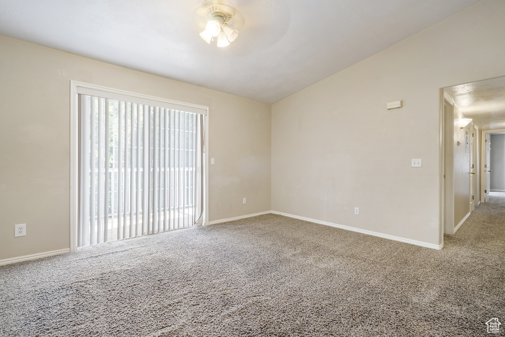 Empty room featuring carpet flooring, vaulted ceiling, and a ceiling fan