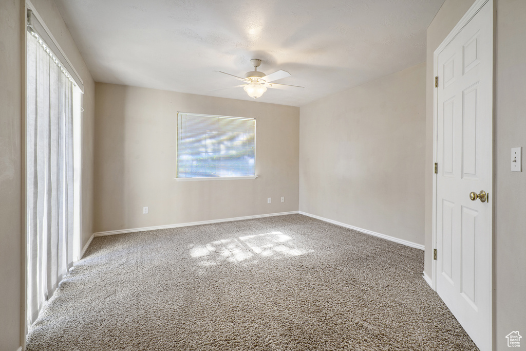 Carpeted empty room with ceiling fan and baseboards