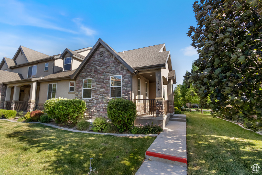 View of front of home with a porch, stone siding, and stucco siding