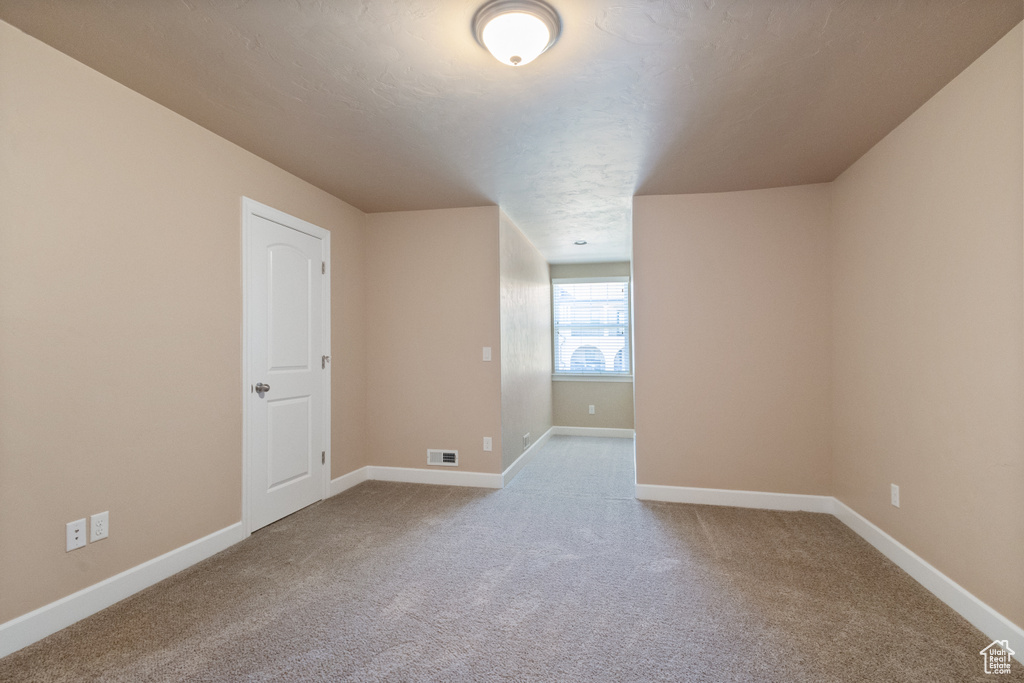 Carpeted spare room featuring baseboards