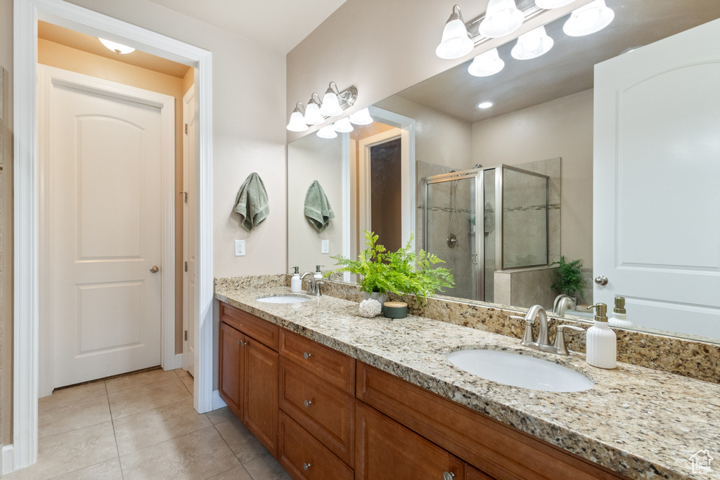 Full bath with double vanity, a shower stall, and tile patterned floors