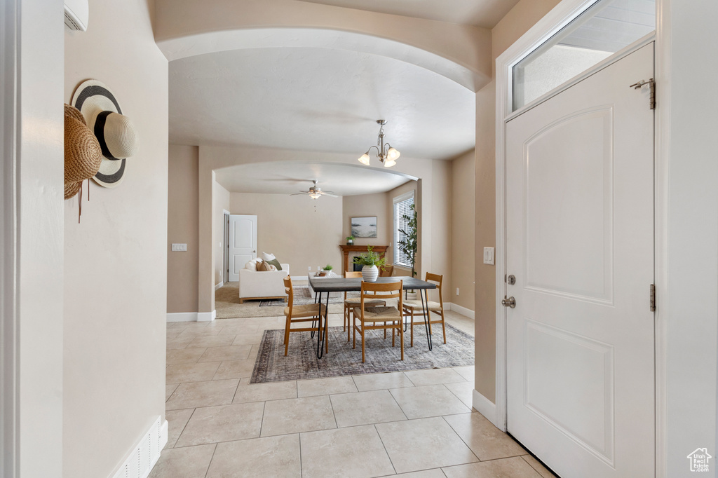 Dining room featuring arched walkways, a chandelier, light tile patterned floors, and ceiling fan