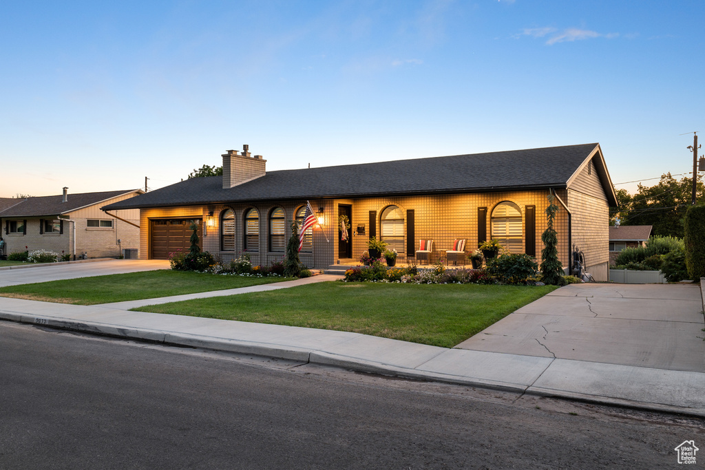 Ranch-style house with concrete driveway, a garage, a front yard, a chimney, and a shingled roof