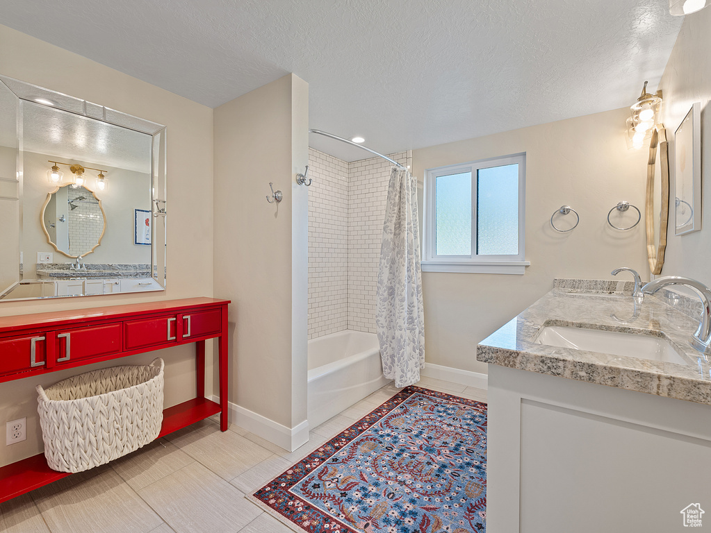 Bathroom with shower / bath combo, a textured ceiling, and double vanity