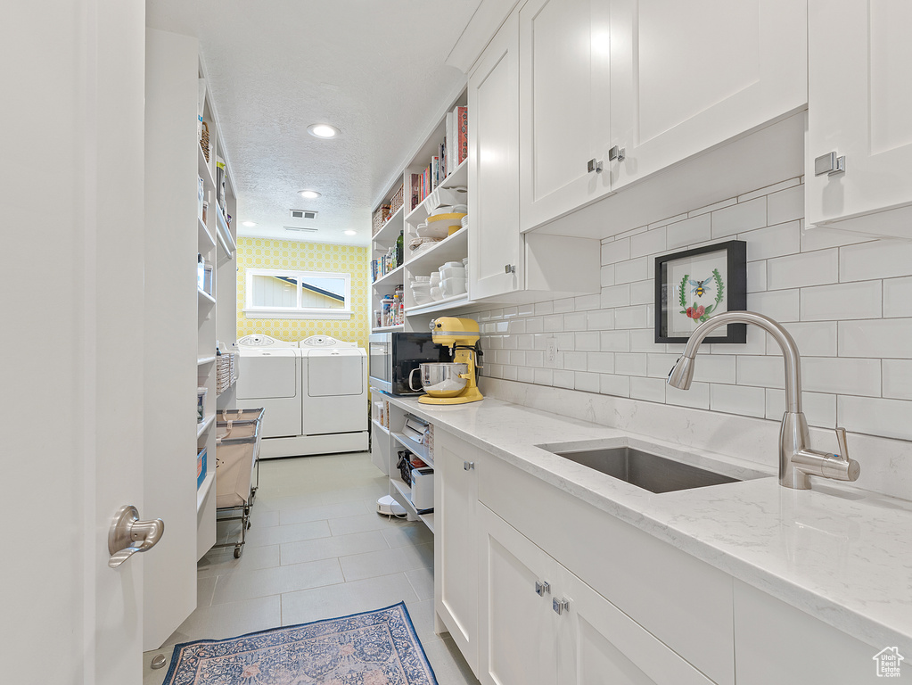 Kitchen with washer and dryer, open shelves, white cabinets, backsplash, and recessed lighting