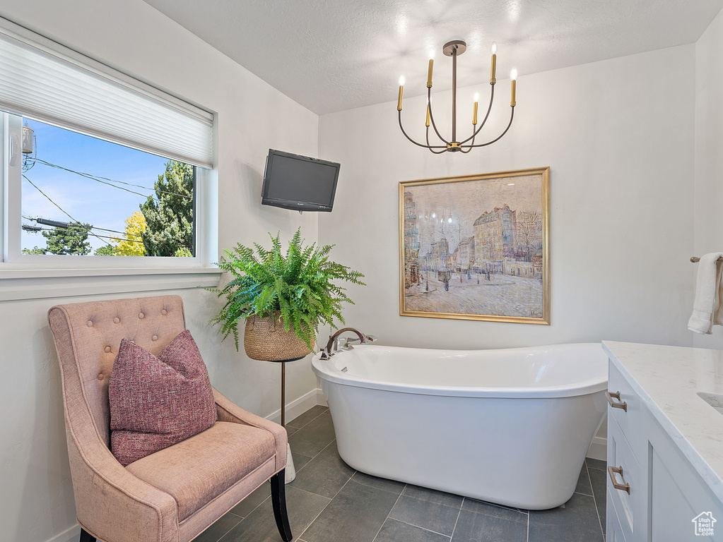 Bathroom with a freestanding bath, vanity, a chandelier, and tile patterned flooring