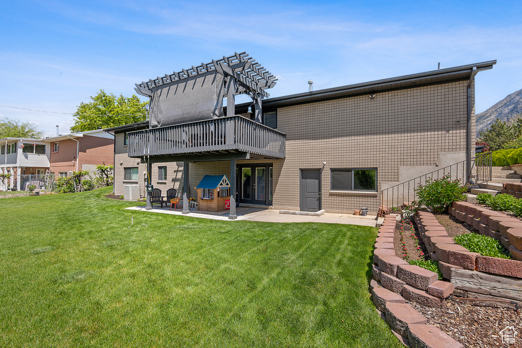 Rear view of property with a lawn, a patio, a wooden deck, and brick siding