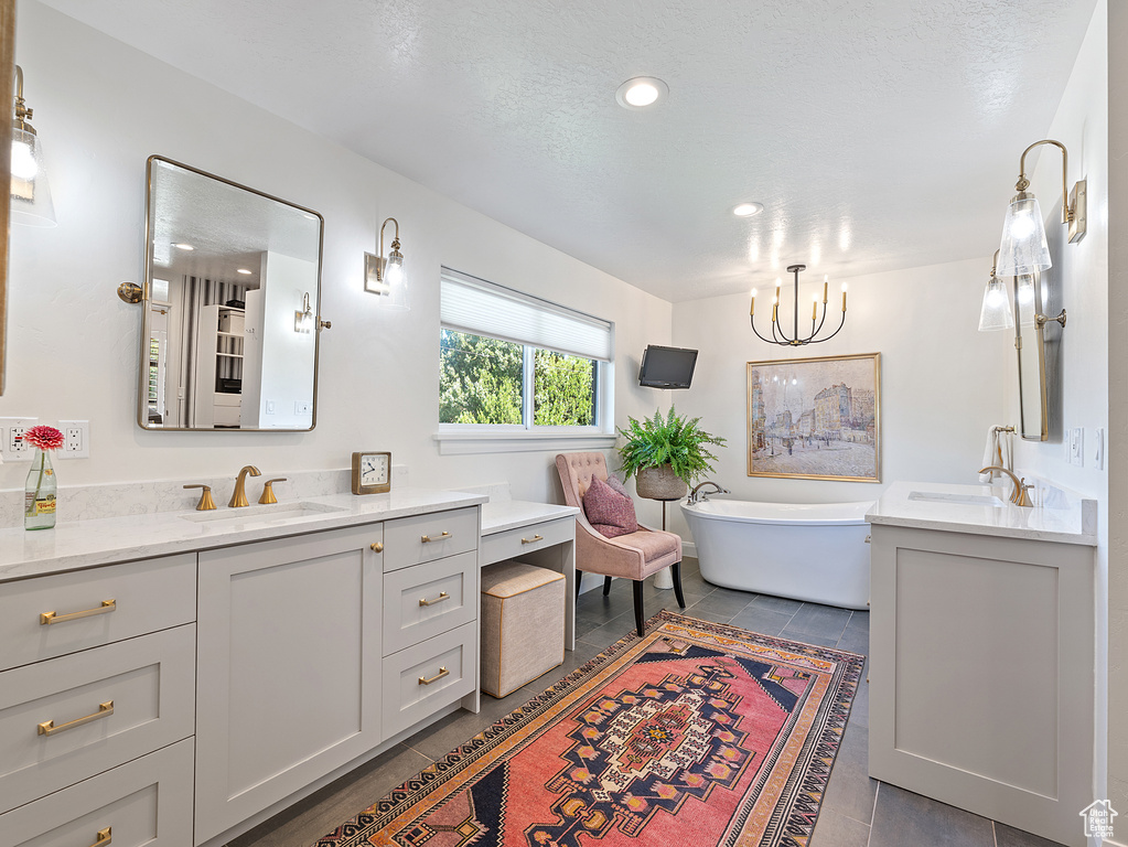 Full bathroom featuring tile patterned floors, vanity, a freestanding tub, and recessed lighting