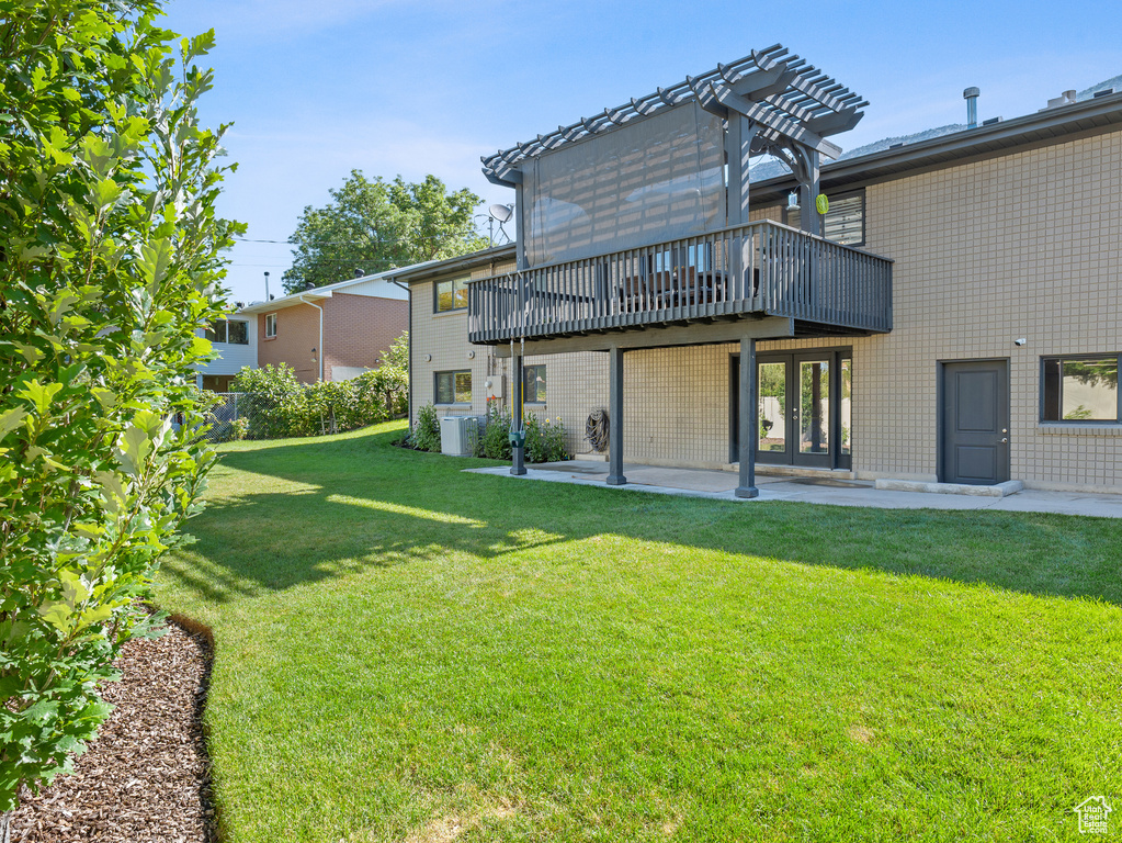 Rear view of property featuring a yard, a deck, and a patio