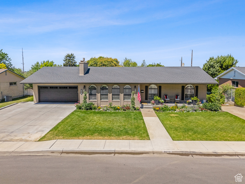 Single story home featuring covered porch, an attached garage, a front yard, a chimney, and driveway