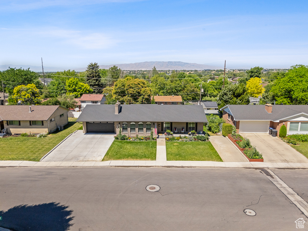 View of front of home with concrete driveway, a garage, a front yard, and a chimney