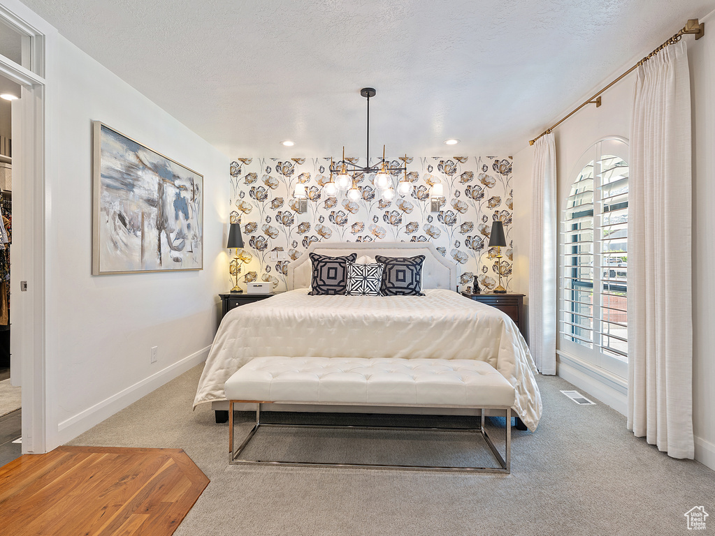 Carpeted bedroom with a chandelier and baseboards