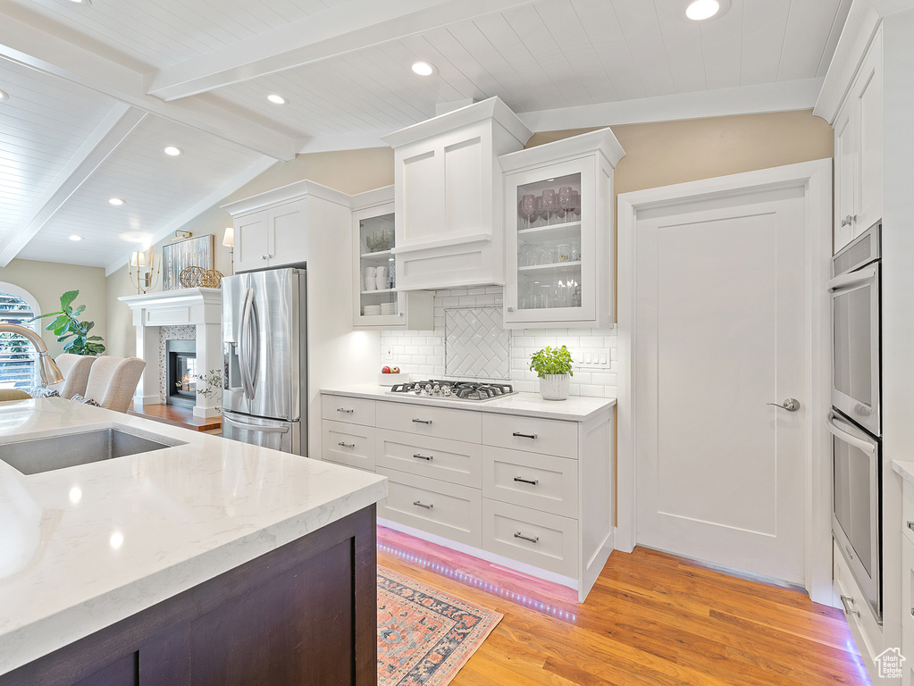 Kitchen with appliances with stainless steel finishes, light wood-type flooring, white cabinetry, backsplash, and recessed lighting