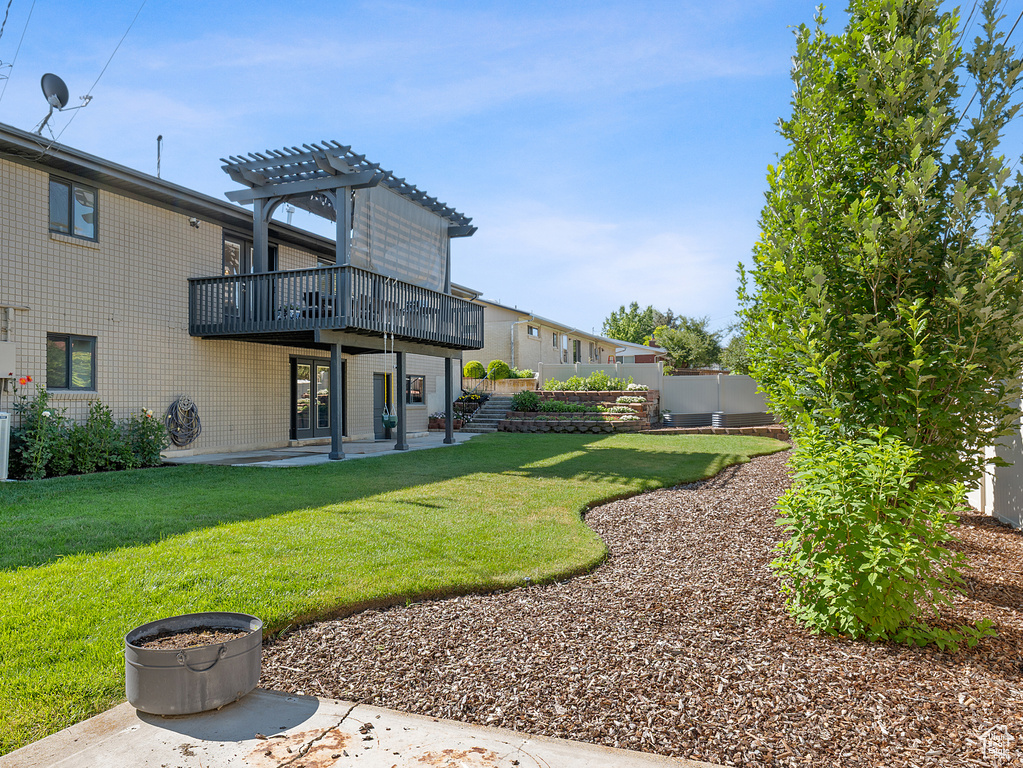 View of green lawn featuring a pergola, a wooden deck, and a patio