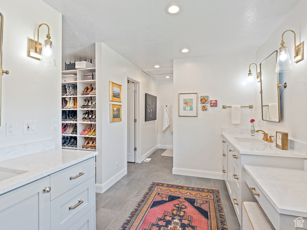 Bathroom featuring two vanities, recessed lighting, and a textured ceiling