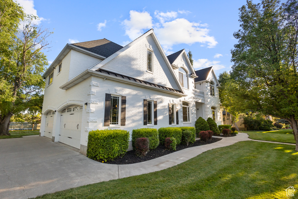 View of home\\\'s exterior with an attached garage, concrete driveway, a standing seam roof, a shingled roof, and a metal roof