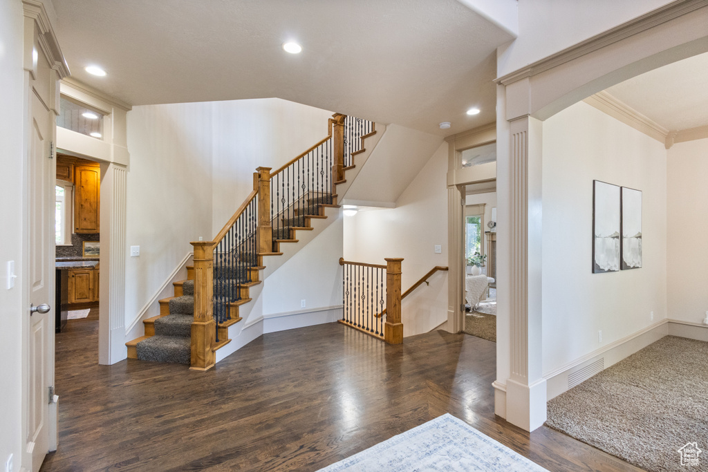 Entrance foyer featuring wood finished floors, recessed lighting, arched walkways, ornamental molding, and stairs