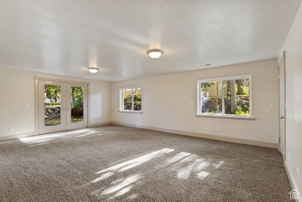 Carpeted spare room featuring baseboards and french doors