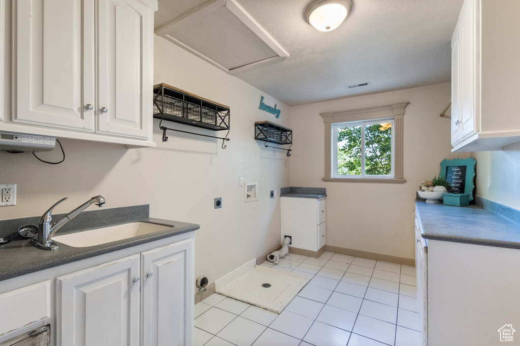 Washroom with hookup for an electric dryer, cabinet space, washer hookup, and light tile patterned floors