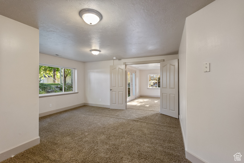 Carpeted spare room featuring baseboards and a textured ceiling