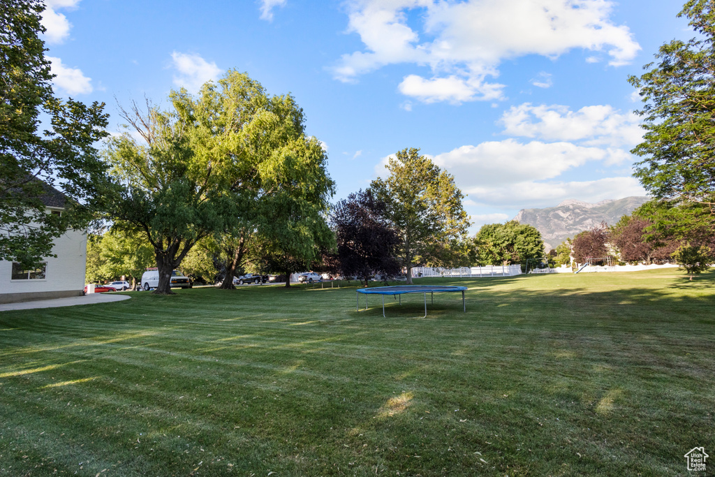 View of grassy yard featuring a trampoline and a mountain view