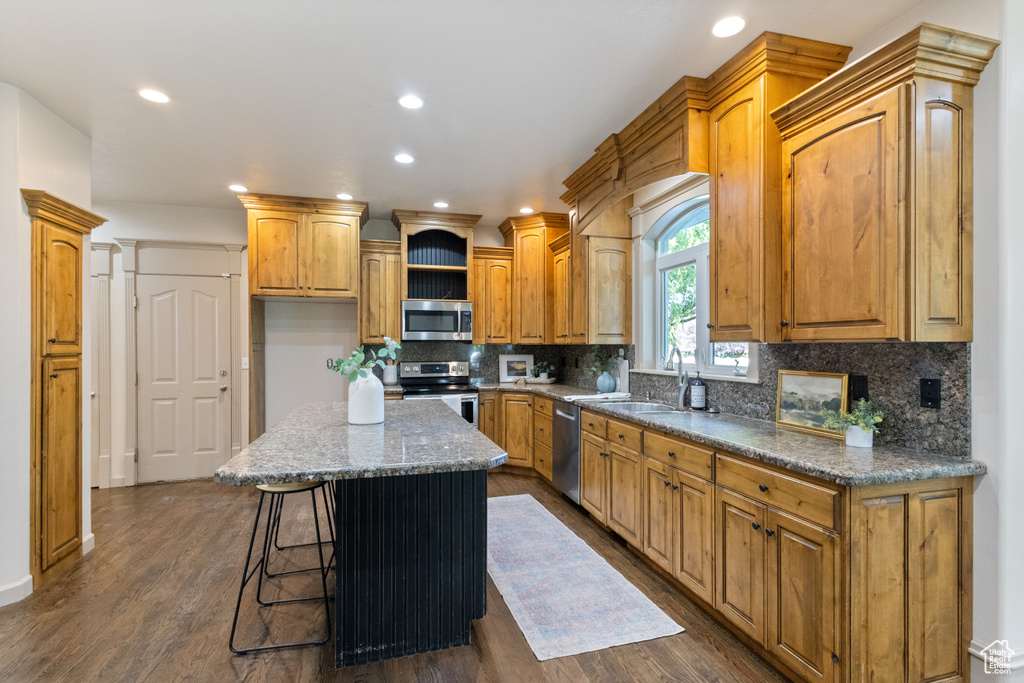 Kitchen featuring stainless steel appliances, a kitchen island, recessed lighting, tasteful backsplash, and dark wood finished floors