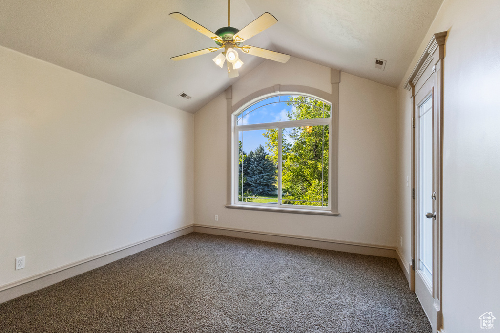 Empty room with lofted ceiling, carpet flooring, and ceiling fan