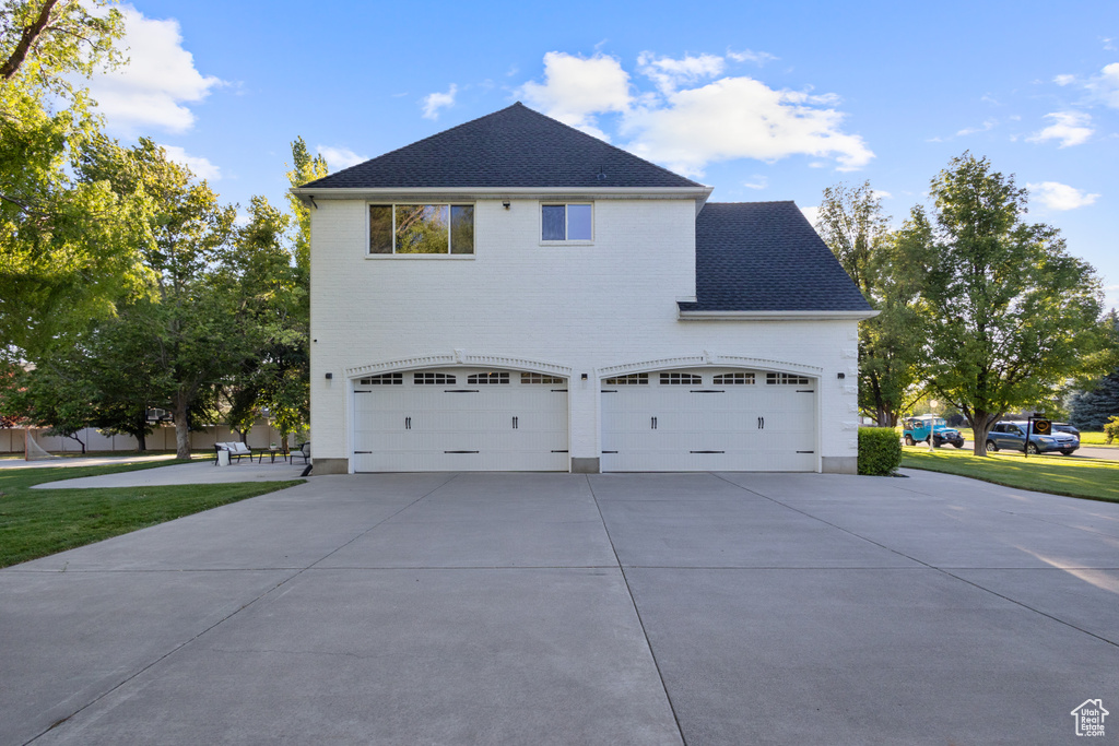 View of property exterior with concrete driveway and roof with shingles