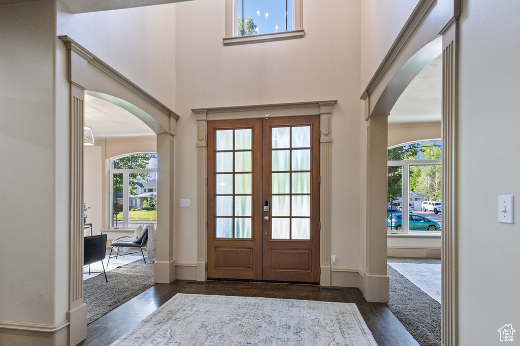 Foyer entrance with arched walkways, dark wood-style floors, plenty of natural light, and a towering ceiling