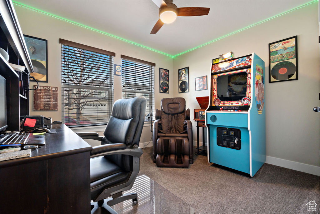 Carpeted office space featuring a ceiling fan and baseboards