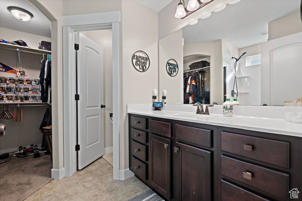 Full bath with vanity, a walk in closet, and tile patterned floors