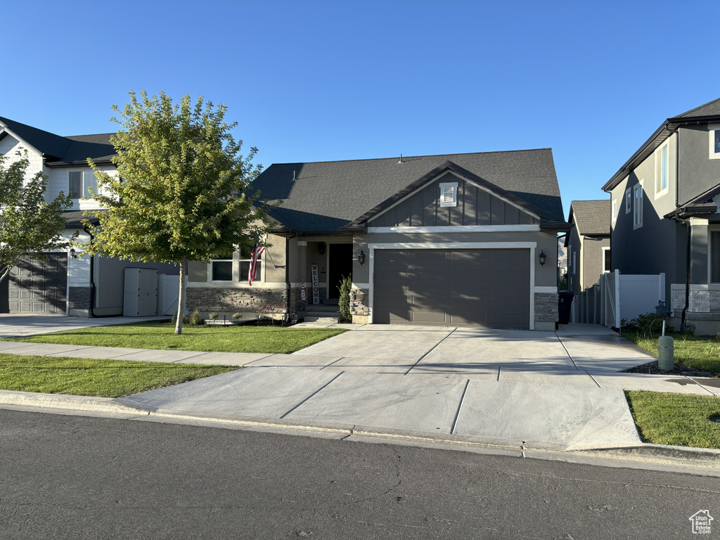 View of front of home featuring concrete driveway, stone siding, an attached garage, and board and batten siding