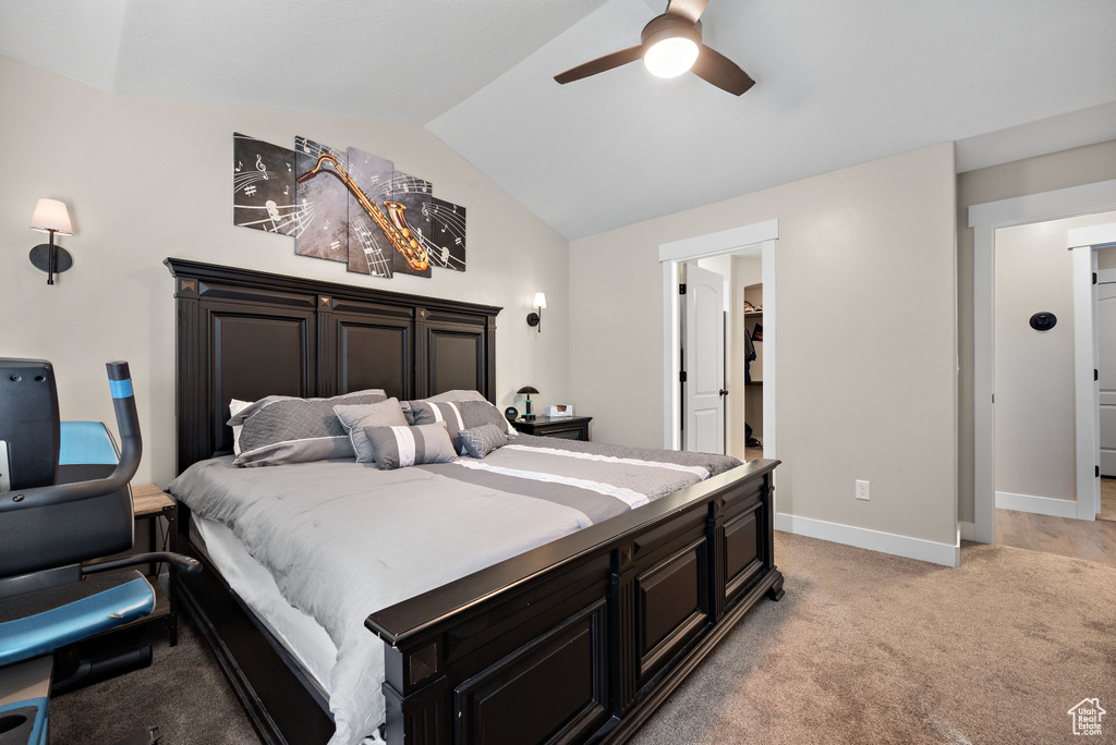 Bedroom with vaulted ceiling, light carpet, a spacious closet, and a ceiling fan