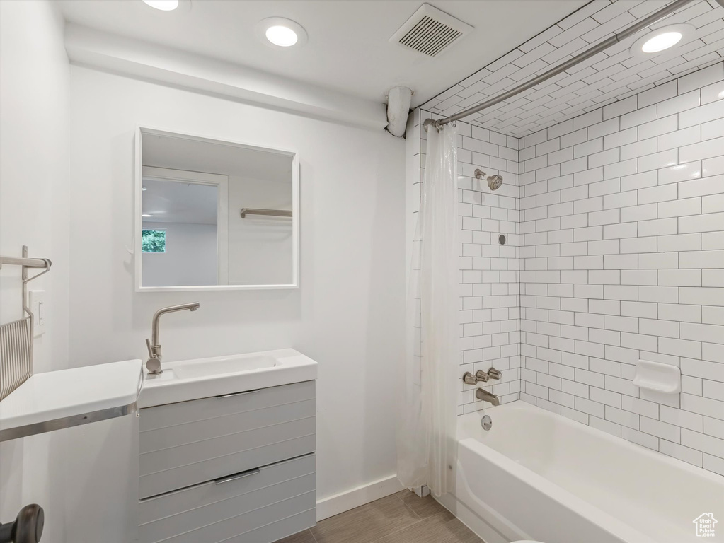 Full bath with vanity, shower / bath combo with shower curtain, wood finished floors, and recessed lighting