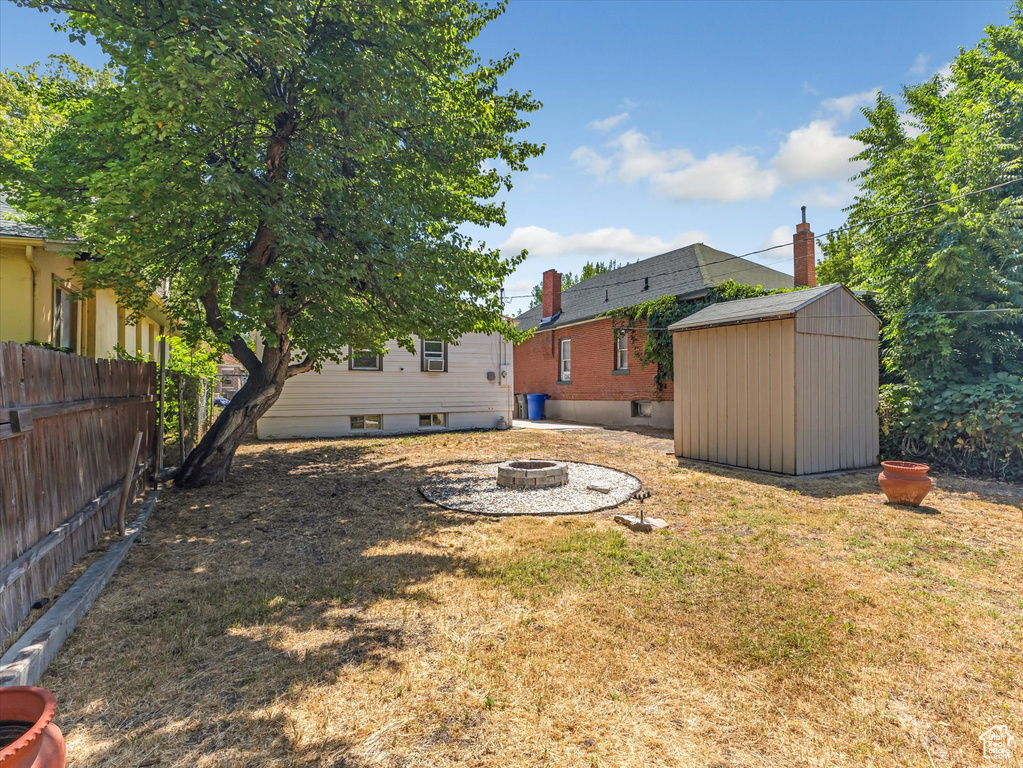 View of yard featuring a fire pit and a storage shed