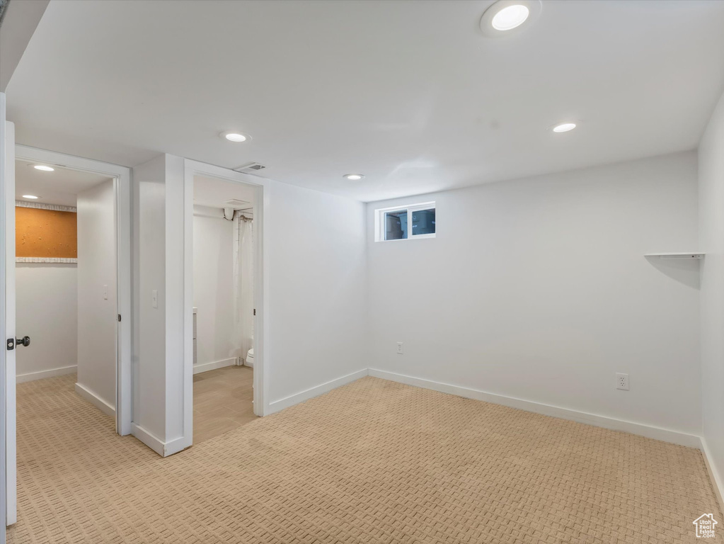 Finished below grade area with light colored carpet and recessed lighting