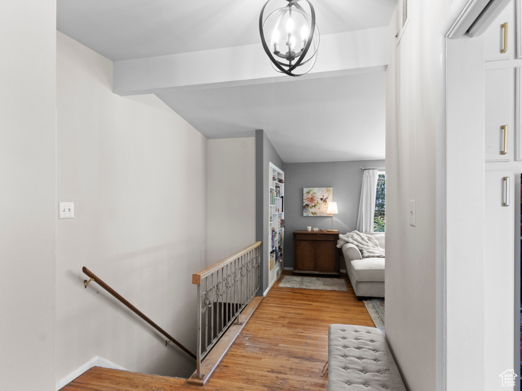Hallway featuring an upstairs landing, light wood-style floors, and a chandelier