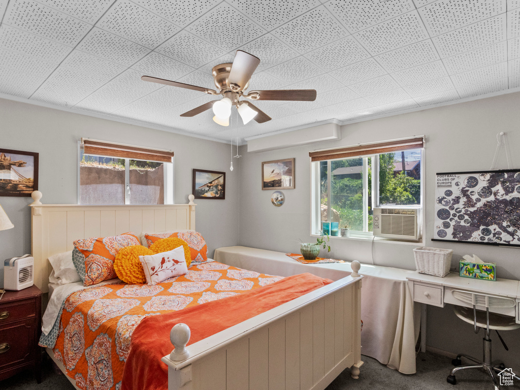 Carpeted bedroom with cooling unit, a ceiling fan, and a desk