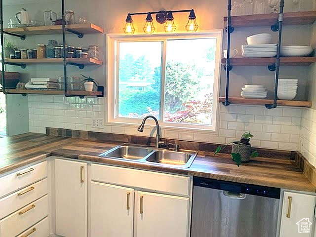Kitchen featuring stainless steel dishwasher, open shelves, white cabinetry, and tasteful backsplash