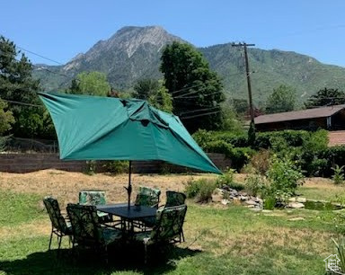 View of grassy yard with a mountain view and outdoor dining space