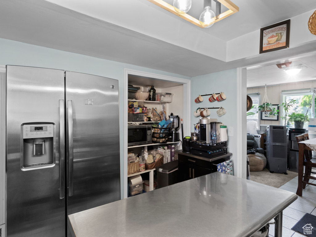 Kitchen with stainless steel fridge with ice dispenser, stainless steel countertops, and light tile patterned floors