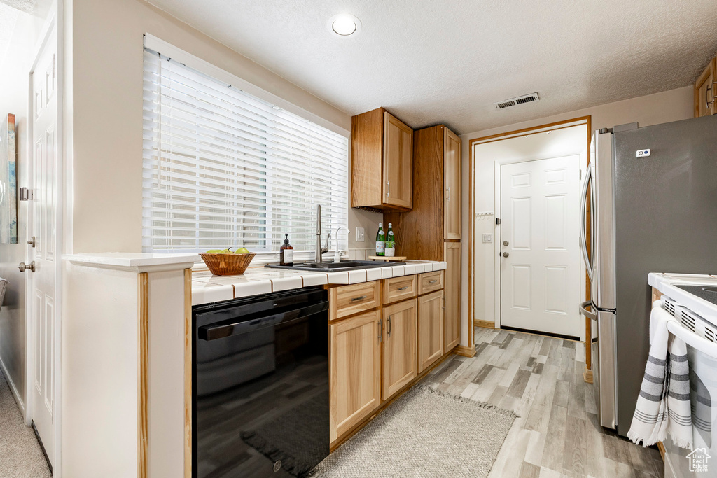 Kitchen with black dishwasher, light wood finished floors, tile counters, recessed lighting, and white electric range oven