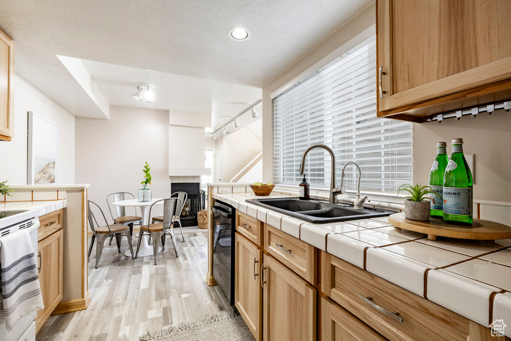 Kitchen with tile counters, dishwasher, light wood-type flooring, electric range, and track lighting