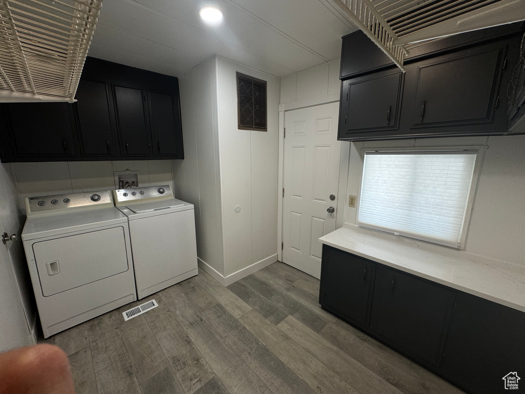 Washroom featuring cabinet space, washer and clothes dryer, and wood finished floors