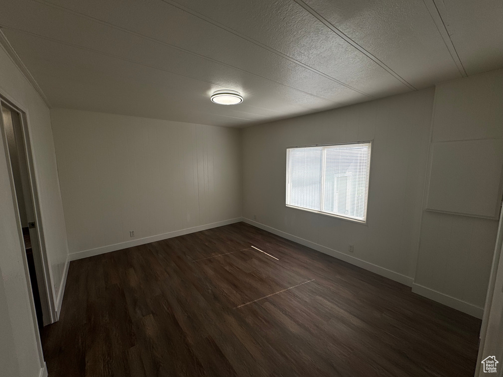 Empty room featuring dark wood-style flooring and a textured ceiling
