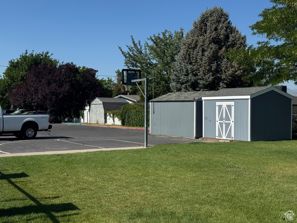 View of sport court with a storage shed and a lawn