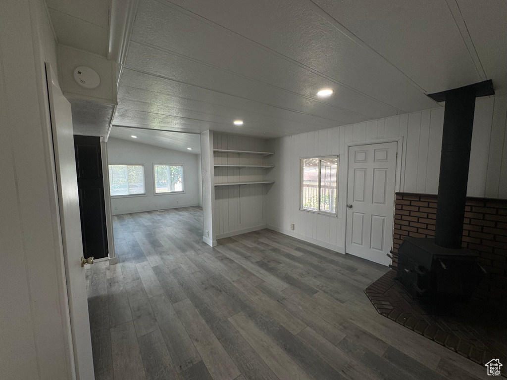 Unfurnished living room featuring wood finished floors, a wood stove, and recessed lighting