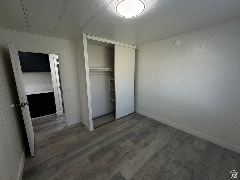 Unfurnished bedroom with wood finished floors and a closet